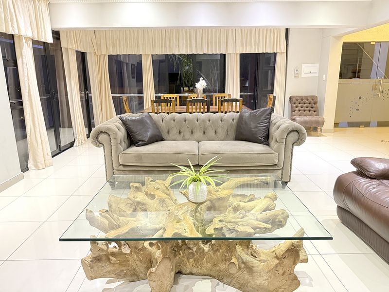 Spacious open-plan living and dining area featuring large sliding glass doors, neutral tiled flooring, and modern recessed lighting.