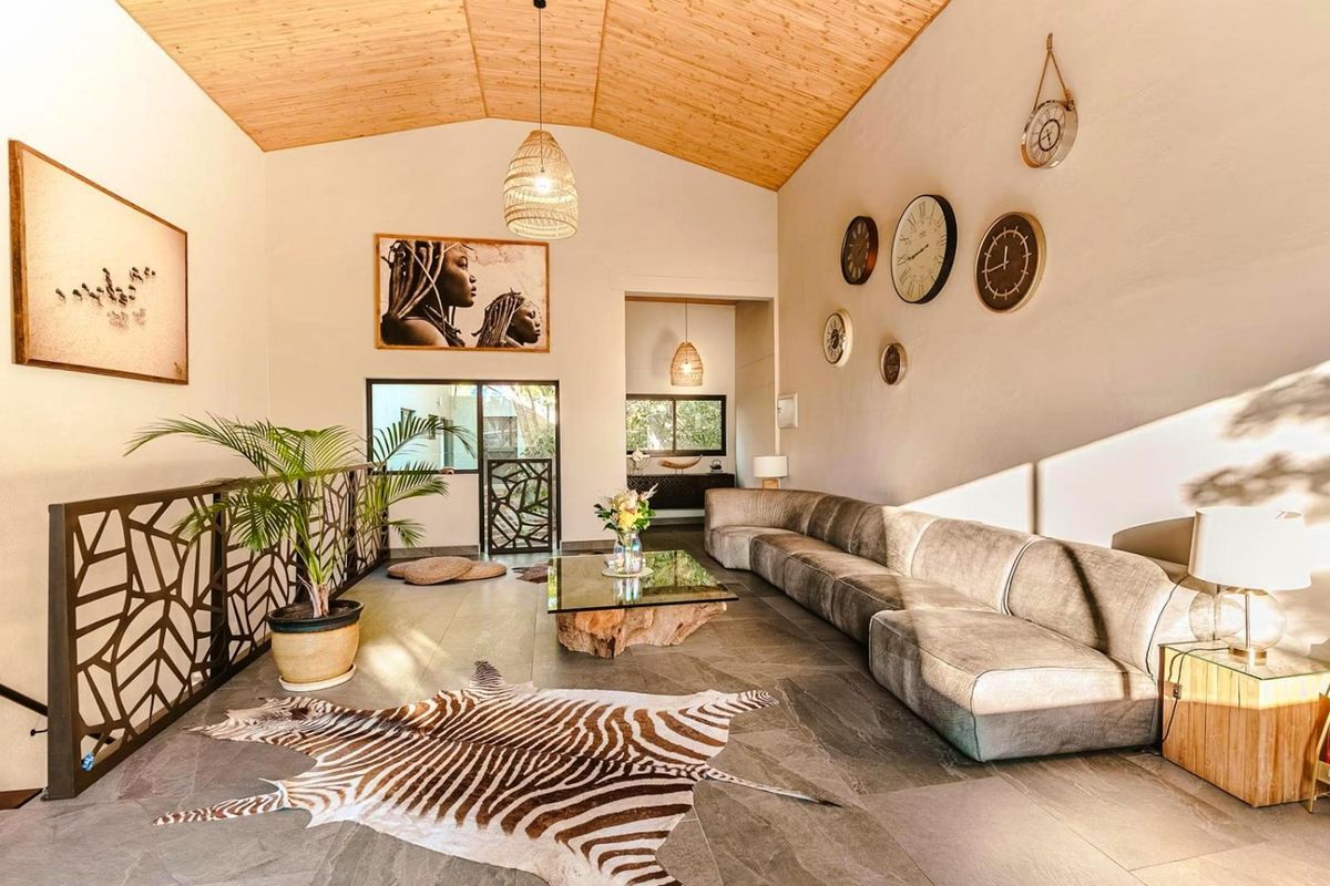 Spacious living area featuring a high vaulted timber ceiling, large format floor tiles, and a decorative metal balustrade overlooking the lower level.