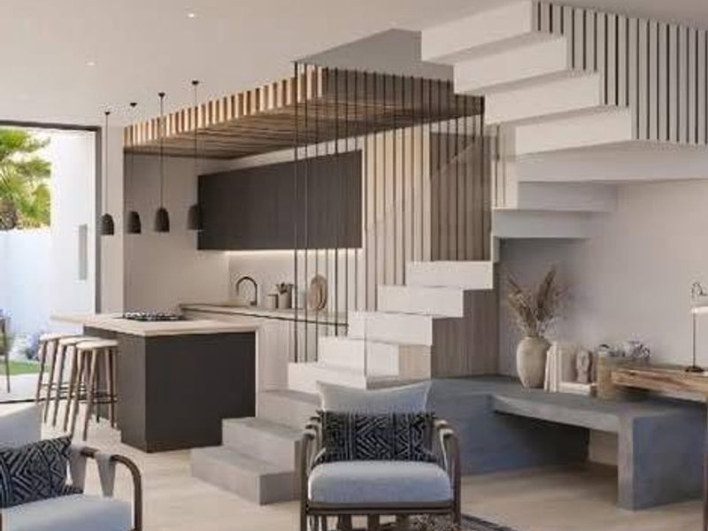 Modern open-plan living area featuring a sleek kitchen with island, architectural staircase, and contemporary finishes throughout.