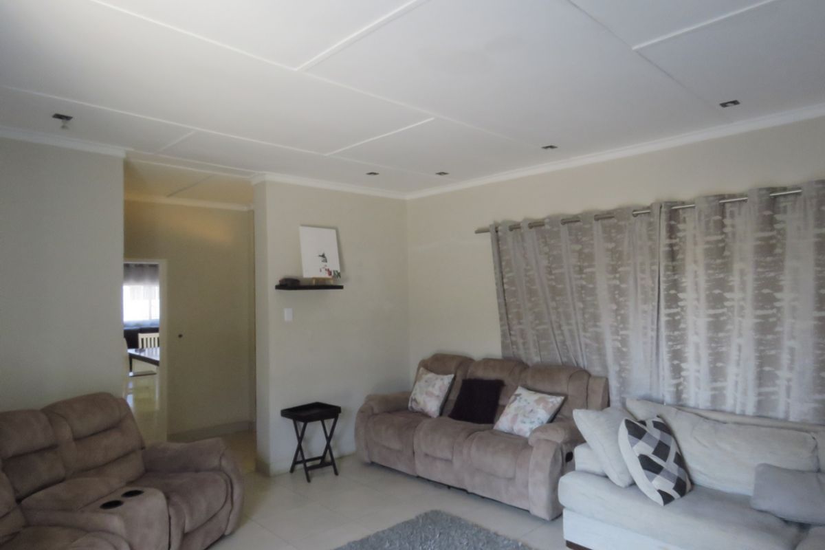 A neutrally painted living room featuring tiled flooring and recessed ceiling lighting, providing a functional and comfortable space.