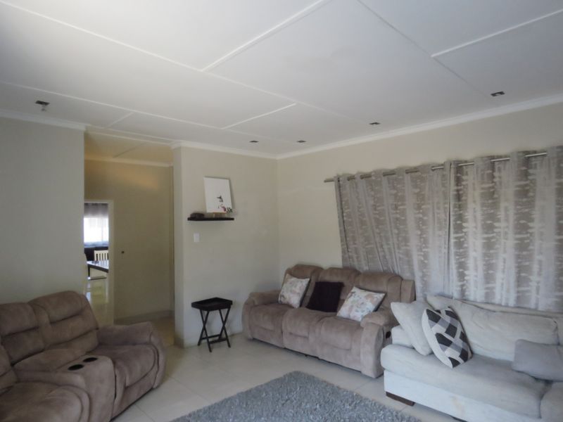 A neutrally painted living room featuring tiled flooring and recessed ceiling lighting, providing a functional and comfortable space.