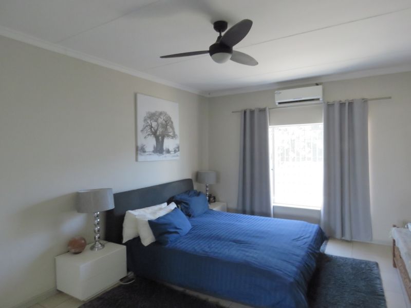A well-maintained bedroom featuring a ceiling fan, split-system air conditioning, and neutral wall finishes.