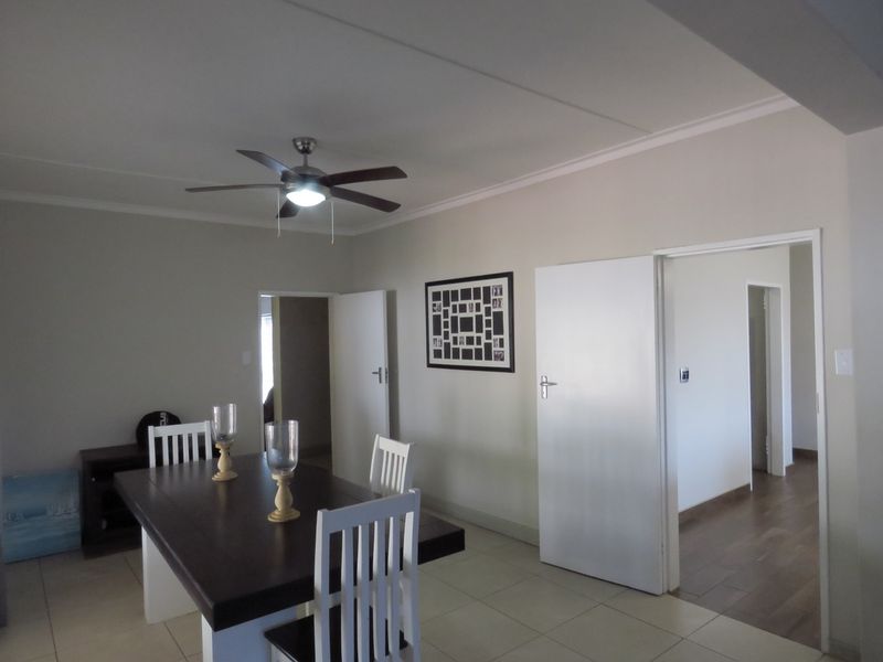 A well-maintained dining area featuring tiled flooring, coved cornicing, and a central ceiling fan, providing access to adjacent rooms through internal doorways.