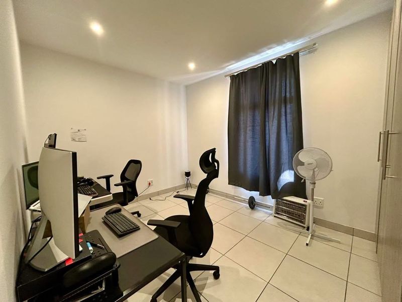 A functional office space featuring tiled flooring, recessed downlighting, and a built-in wardrobe for storage.