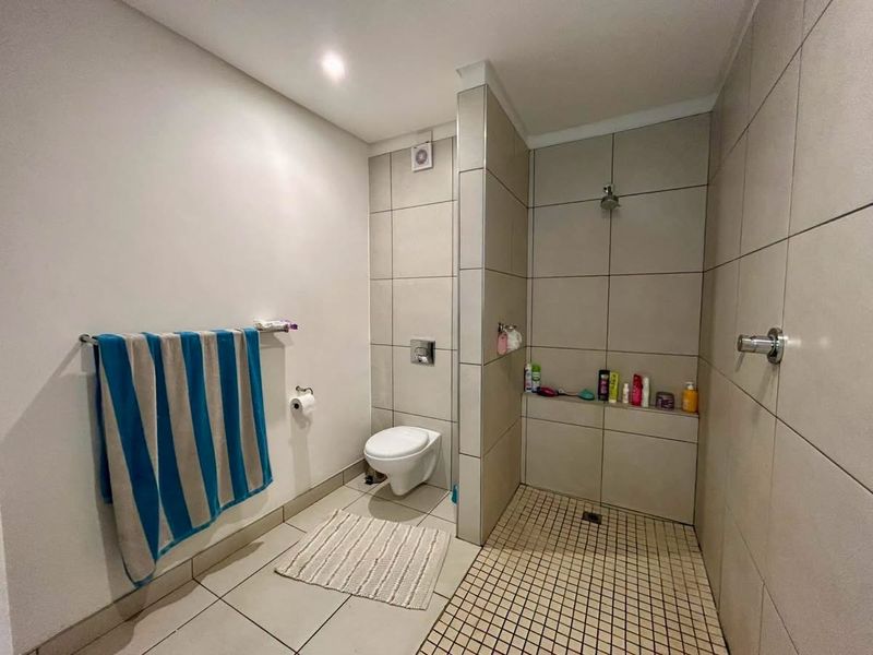 Modern bathroom featuring a walk-in shower with tiled walls, a wall-mounted toilet, and a recessed storage shelf.