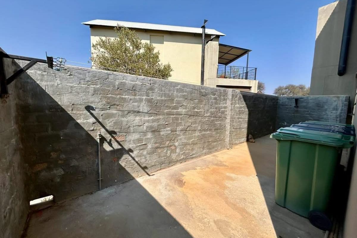 A private rear courtyard area featuring a concrete surface and a high brick boundary wall, providing a functional outdoor utility space.