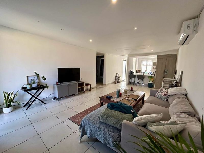 Spacious open-plan living area featuring tiled floors, recessed lighting, and a split-system air conditioner, seamlessly connecting to the kitchen and breakfast bar area.