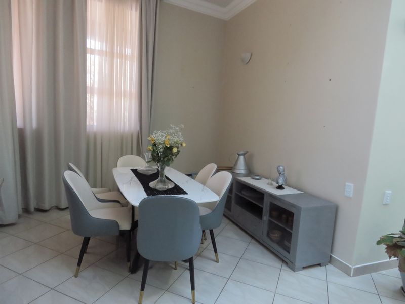 A bright dining area featuring tiled flooring, neutral wall tones, and elegant cove cornicing, providing a clean and functional space for meals.