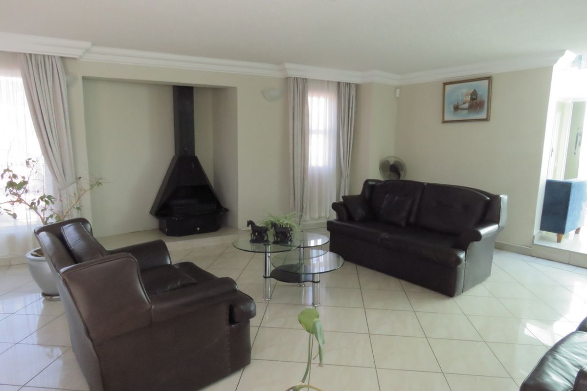 Spacious living room featuring tiled flooring, crown molding, and a prominent black freestanding fireplace.
