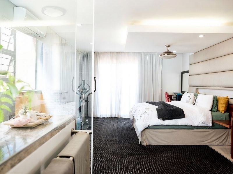 Spacious bedroom featuring a large upholstered headboard, recessed ceiling lighting, a ceiling fan, and an integrated glass partition wall.