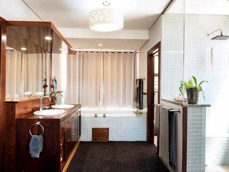 A well-appointed bathroom featuring a double vanity with wooden cabinetry, a built-in bathtub, and a separate walk-in shower with mosaic tiling.