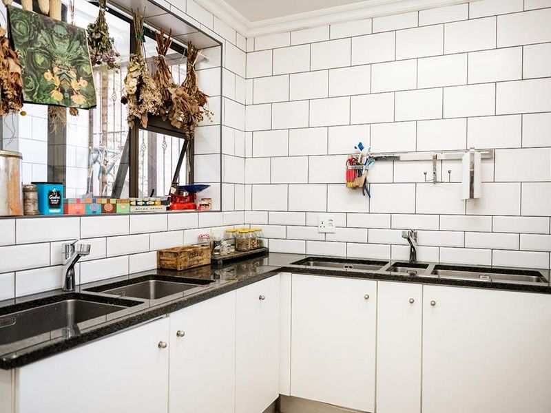A functional kitchen featuring white cabinetry, dark granite countertops, a double stainless steel sink, and a classic white subway tile backsplash.