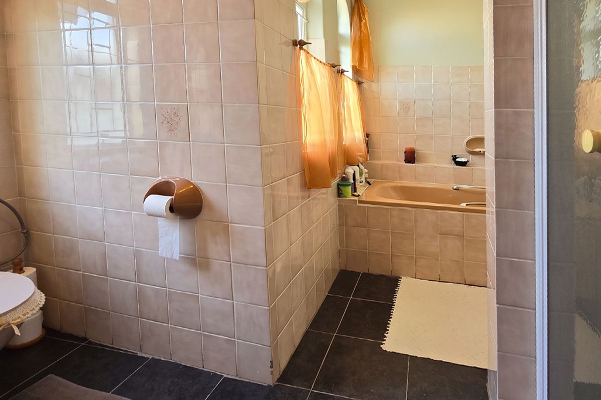 A functional bathroom featuring a built-in bathtub, tiled walls and flooring, and a separate shower enclosure, showcasing a traditional design aesthetic.