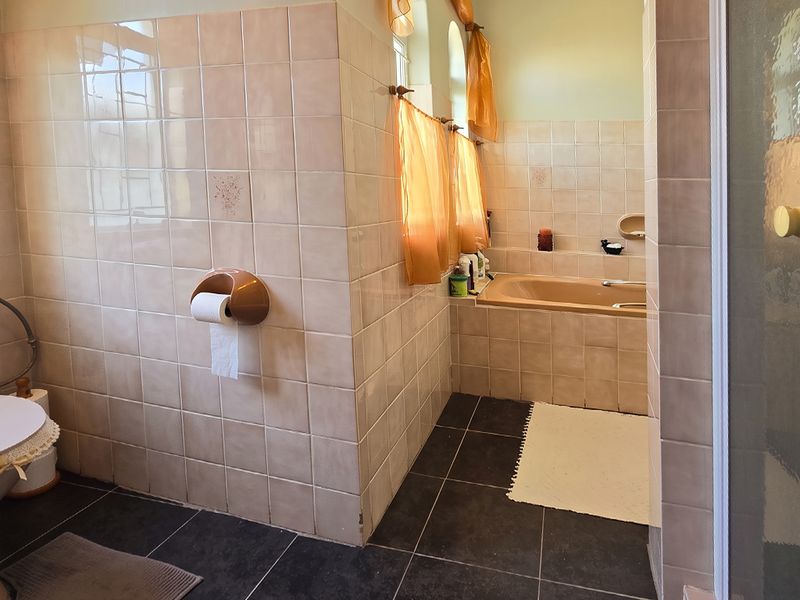 A functional bathroom featuring a built-in bathtub, tiled walls and flooring, and a separate shower enclosure, showcasing a traditional design aesthetic.
