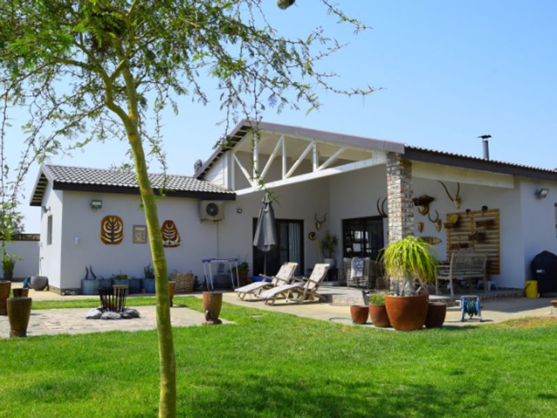 Rear view of the property featuring a spacious covered patio, paved fire pit area, and well-maintained garden space.