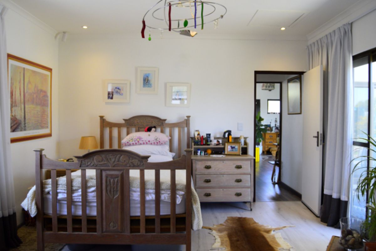 A well-maintained bedroom featuring laminate flooring, recessed downlighting, and a sliding glass door providing natural light and access to the exterior.