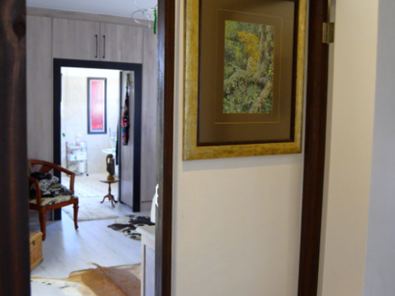 A view through a hallway leading into a bedroom featuring laminate flooring and dark wood door frames.