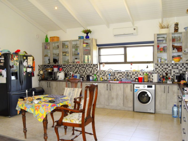 A functional kitchen featuring built-in cabinetry, a tiled backsplash, integrated washing machine, and an exposed beam ceiling with an air conditioning unit.