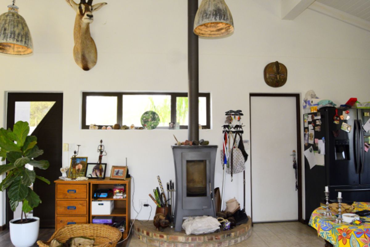 Living area featuring a central freestanding fireplace on a brick hearth, high ceilings with exposed beams, and a horizontal window providing natural light.