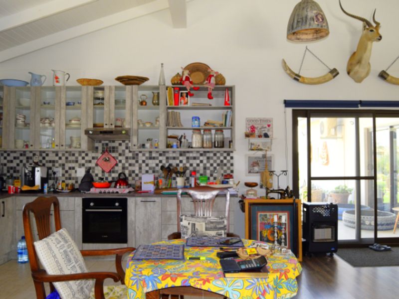 A functional kitchen featuring built-in cabinetry, a checkered tile backsplash, and a vaulted ceiling with direct access to an outdoor patio area.