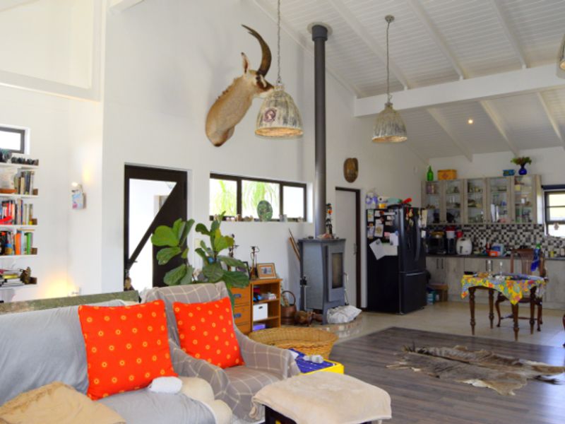 Spacious open-plan living area featuring a vaulted ceiling with exposed beams, a central freestanding fireplace, and a functional kitchen with built-in cabinetry.