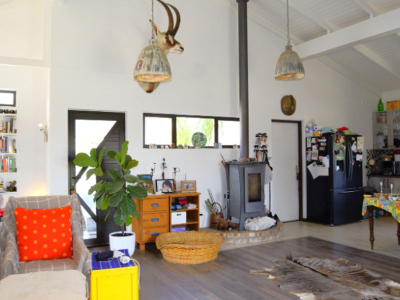 Spacious open-plan living area featuring a vaulted ceiling with exposed rafters, a central wood-burning stove, and an integrated kitchen space.