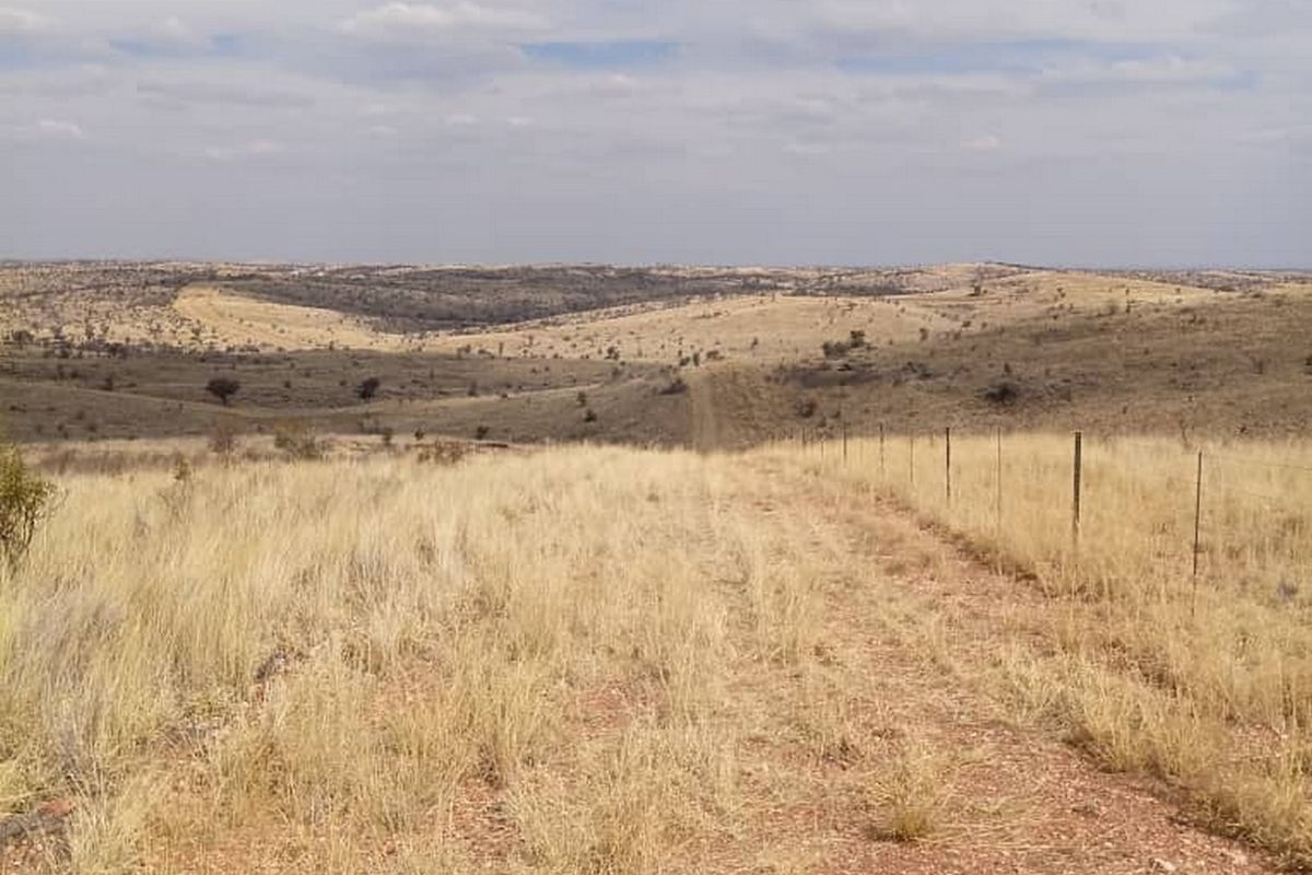 Expansive view of open, undeveloped residential land featuring natural dry grass terrain and a perimeter wire fence.