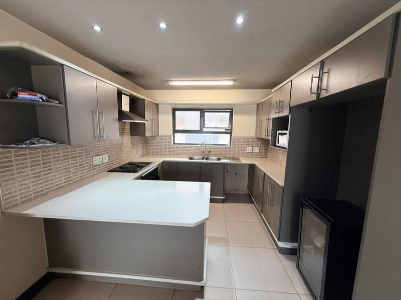 A functional U-shaped kitchen featuring built-in cabinetry, laminate countertops, a double basin sink, and a built-in hob with an extractor fan.