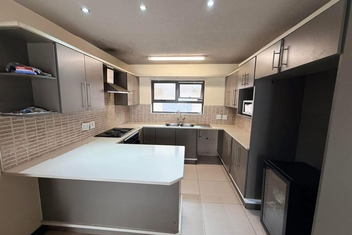 A functional U-shaped kitchen featuring built-in cabinetry, laminate countertops, a double basin sink, and a built-in hob with an extractor fan.