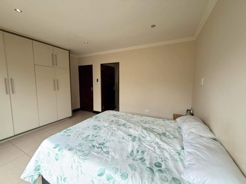 A well-maintained bedroom featuring neutral walls, tiled flooring, recessed lighting, and ample built-in cupboard storage space.
