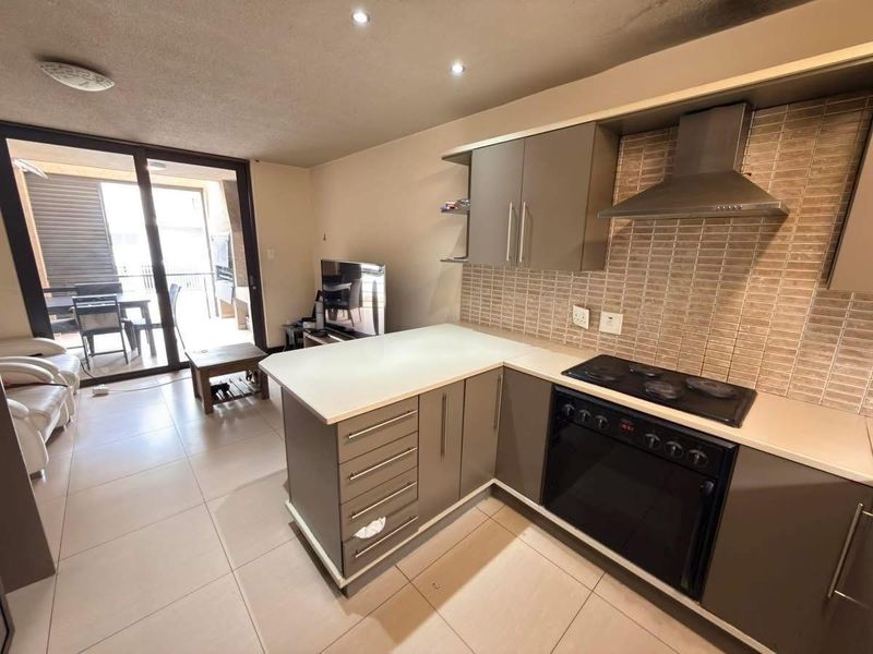 Modern open-plan kitchen featuring sleek cabinetry, stone countertops, integrated appliances, and a seamless transition to the outdoor balcony area.