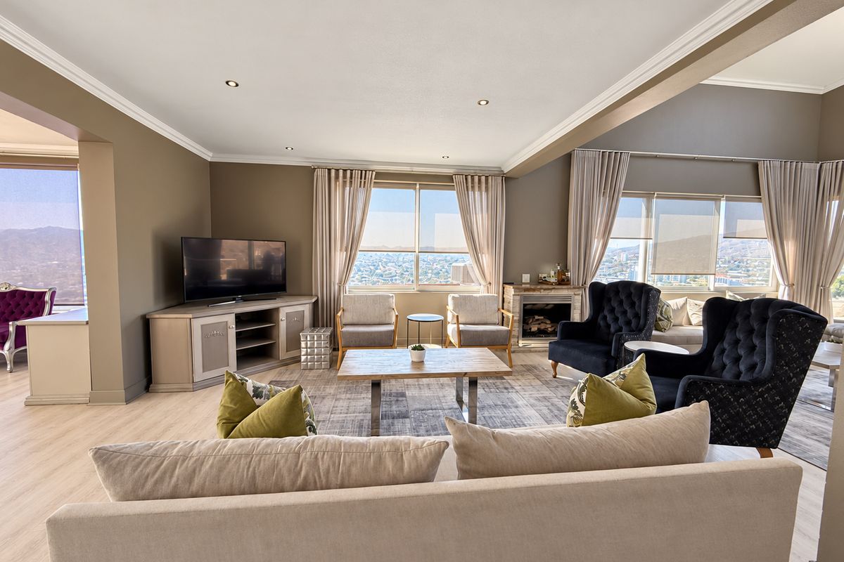 Spacious living room featuring laminate flooring, crown molding, recessed lighting, and a fireplace, with large windows offering expansive views.