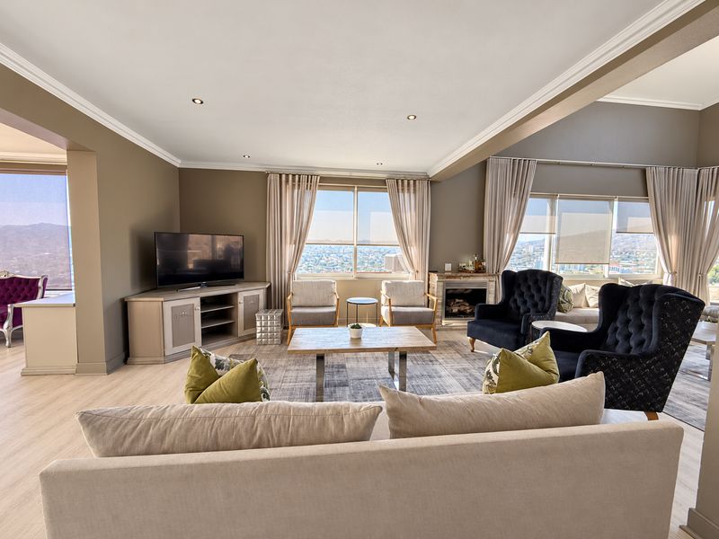 Spacious living room featuring laminate flooring, crown molding, recessed lighting, and a fireplace, with large windows offering expansive views.