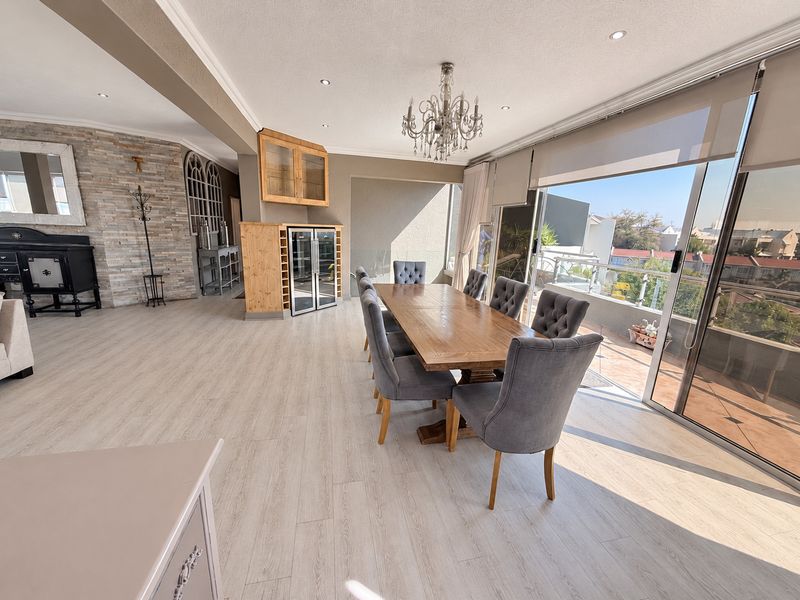Spacious open-plan dining area featuring a stone accent wall, built-in wine storage, and large sliding doors opening to a balcony with natural light.