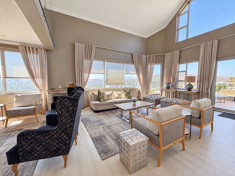 Spacious living room with vaulted ceilings, large windows offering panoramic views, and a fireplace, creating a bright and airy atmosphere.