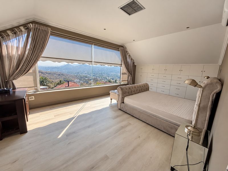 Spacious bedroom featuring extensive built-in cabinetry, light laminate flooring, and a large picture window offering expansive elevated views.