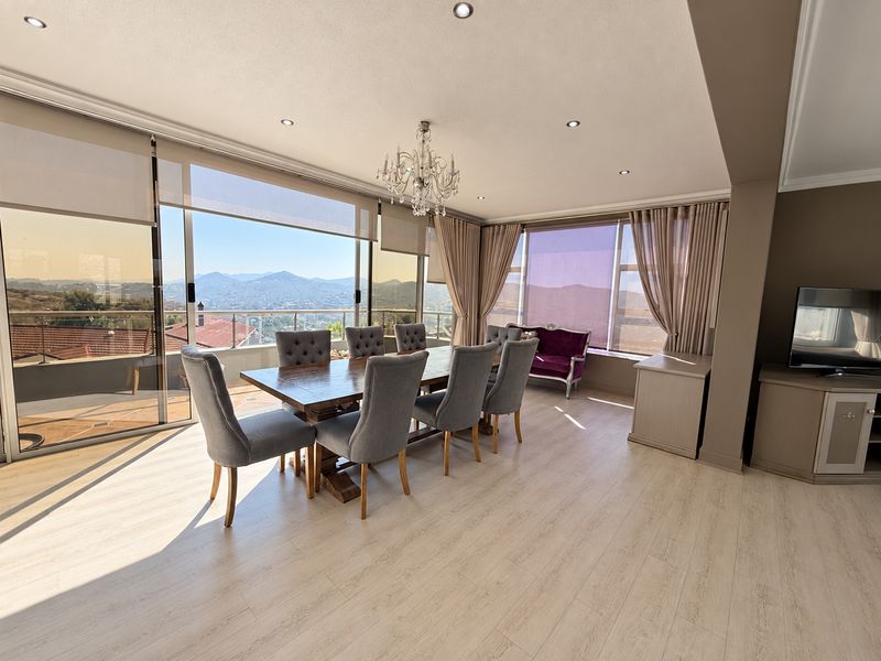 Spacious dining area featuring light laminate flooring, recessed lighting, and large sliding glass doors opening to a balcony with expansive mountain views.