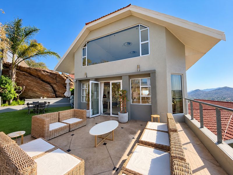 Spacious elevated patio area featuring tiled flooring, metal railings, and direct access to the interior through large glass sliding doors.