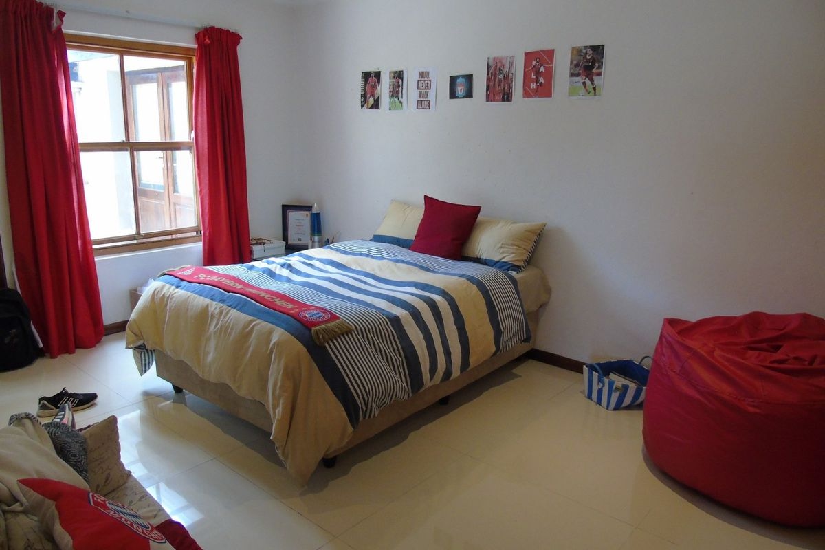 A bedroom featuring tiled flooring and a wooden window frame, providing a functional space with neutral wall finishes.