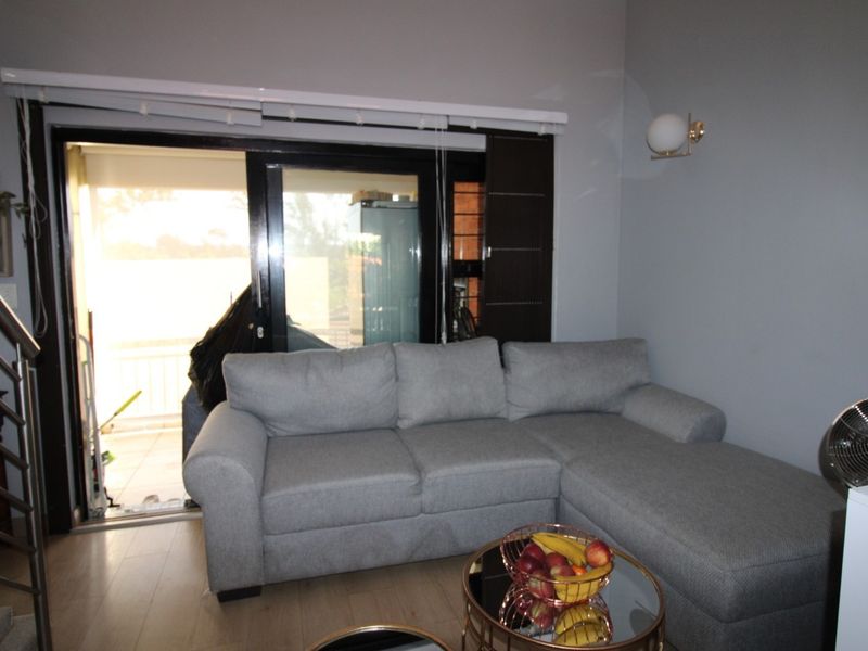 A comfortable living room featuring laminate flooring and a large sliding glass door that provides access to an outdoor balcony area.