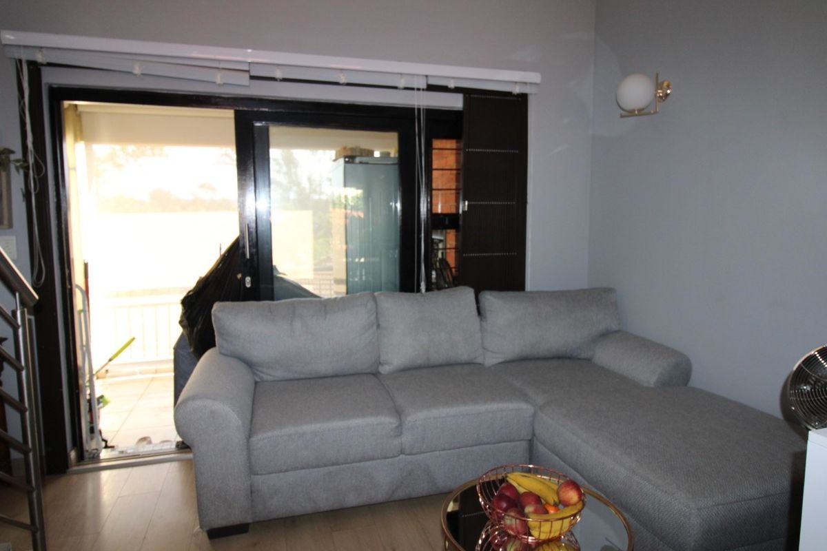 A comfortable living room featuring laminate flooring and a large sliding glass door that provides access to an outdoor balcony area.