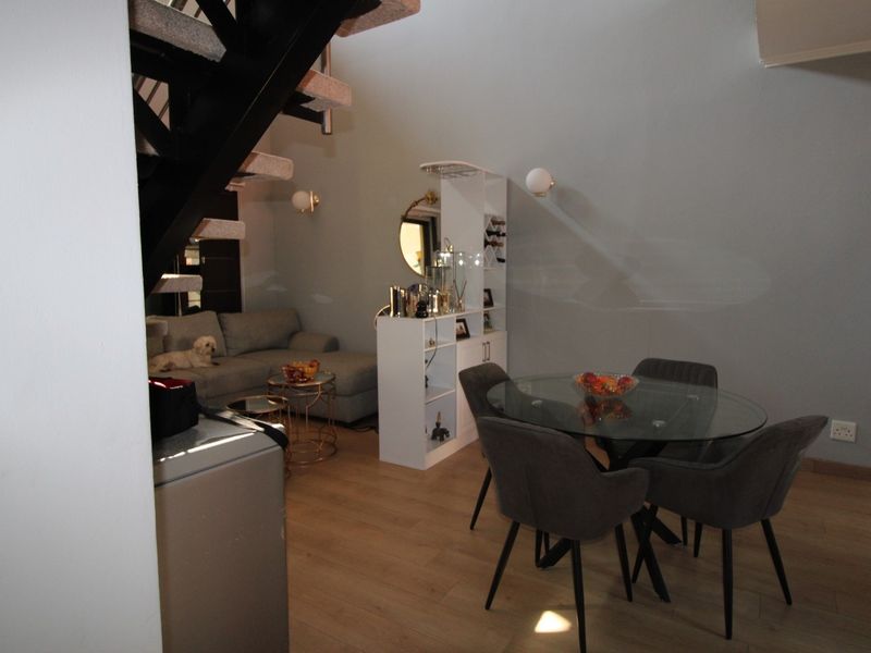 Open plan living and dining area featuring modern laminate flooring and a striking black metal staircase leading to the upper level.