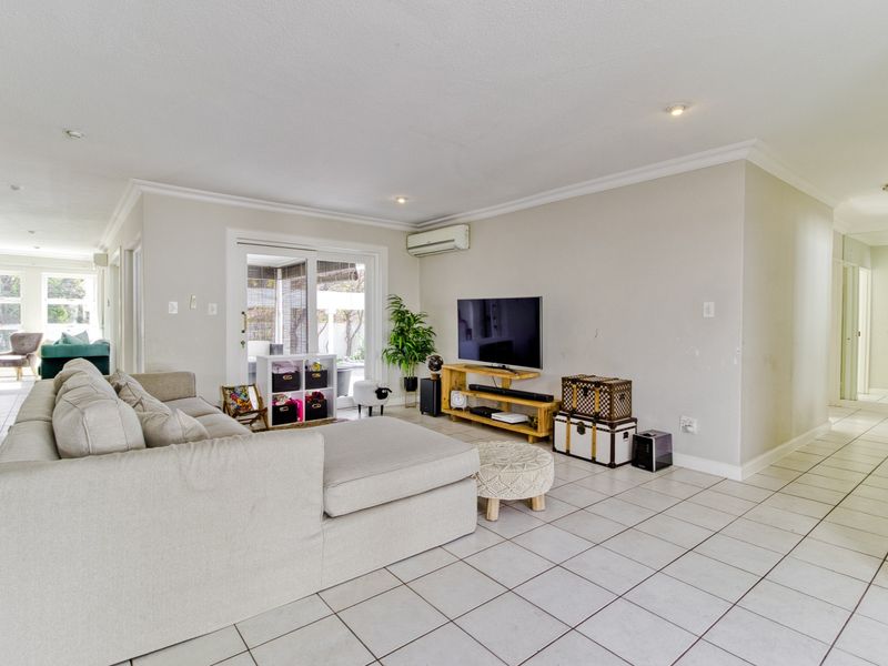 Spacious living room featuring neutral tiled flooring, recessed lighting, and a sliding glass door providing access to the outdoor area.
