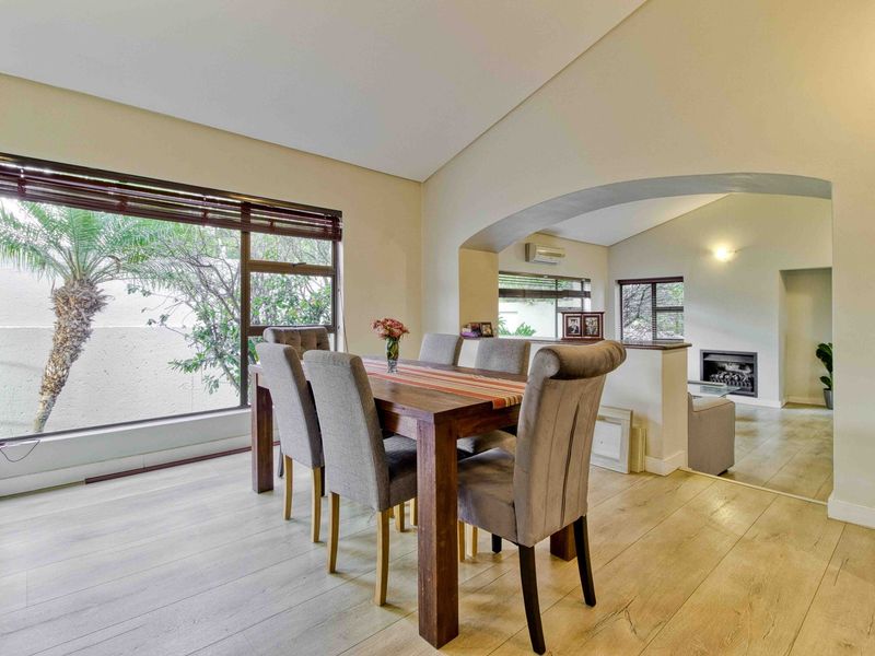 Spacious open-plan dining and living area featuring light laminate flooring, a decorative archway, and a built-in fireplace.