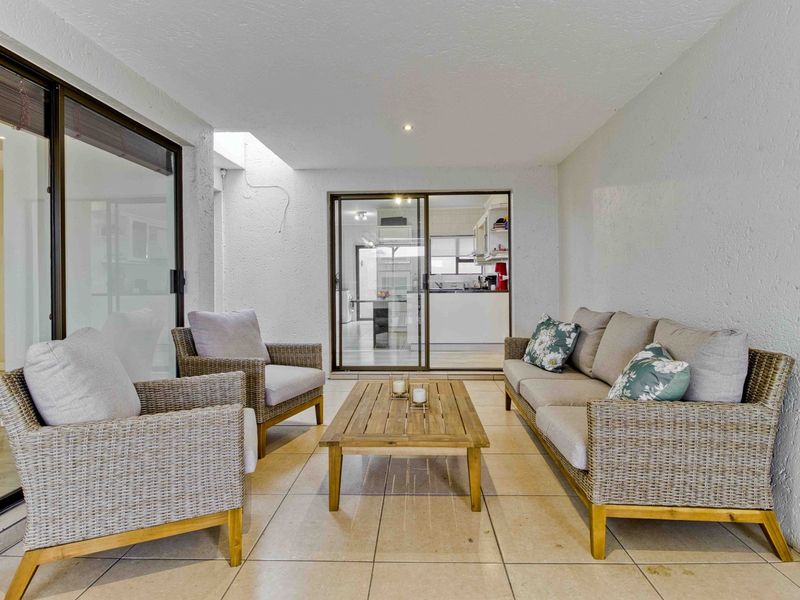 A covered patio area featuring tiled flooring and sliding glass doors, providing a seamless transition to the interior living space.