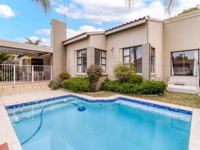 Rear exterior view featuring a swimming pool with tiled surround, a covered patio area, and direct access to the home via sliding glass doors.