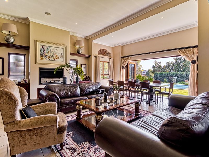 Spacious open-plan living and dining area featuring a built-in fireplace, recessed lighting, and large sliding doors opening to the garden and pool area.