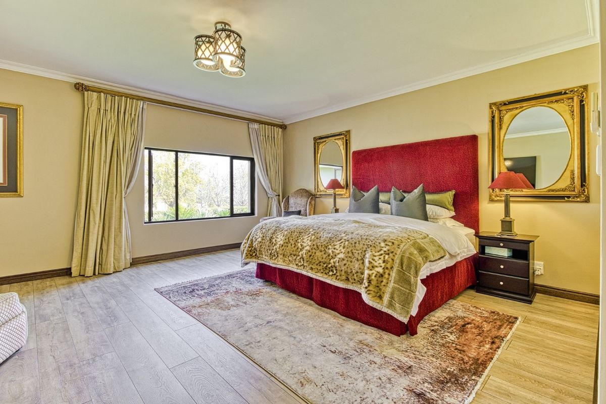 Spacious bedroom featuring light-toned laminate flooring, neutral walls, and a large window providing natural light.