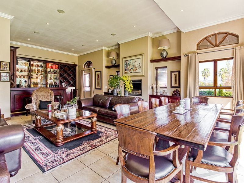 Spacious open-plan living and dining area featuring a built-in bar, wine storage, tiled flooring, and large windows with natural light.