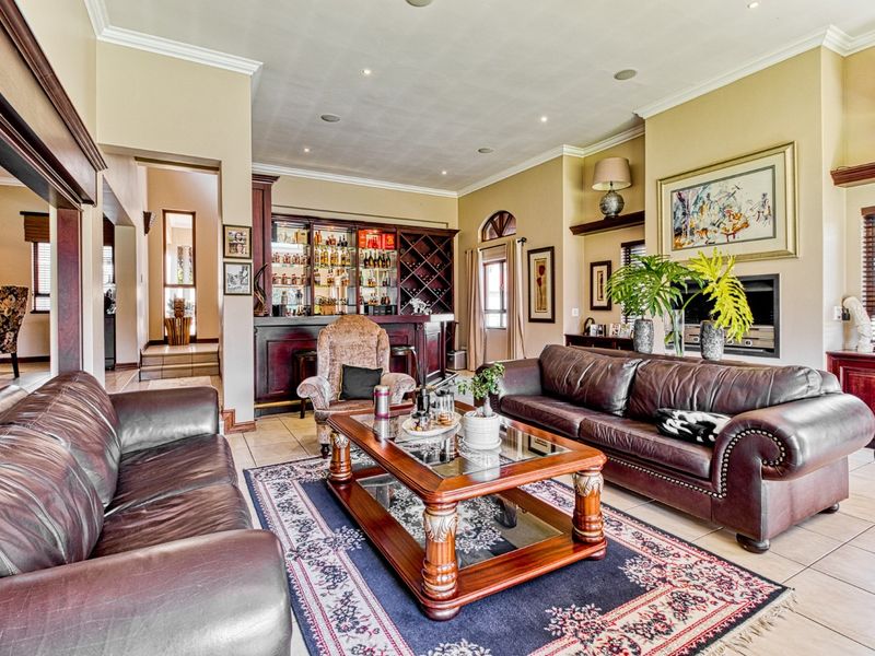 Spacious living room featuring a built-in bar, fireplace, tiled flooring, and crown molding, creating a comfortable and inviting entertainment space.
